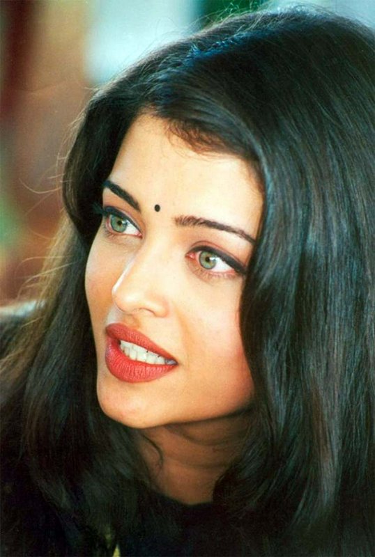 Close up candid portrait of young Aishwarya Rai with a bindi, long dark hair and light green eyes