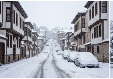 Steep snow-covered residential street lined with historic Ottoman homes as snow falls on parked cars