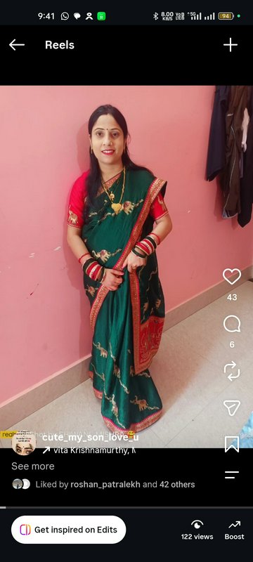 Smiling Indian woman in a dark green embroidered saree poses against a pink wall in an Instagram ...