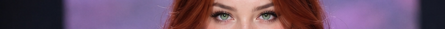 Wide banner crop closeup of pale green eyes and wavy red hair against a soft purple background