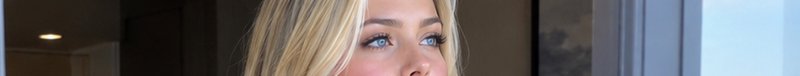 Extreme wide banner close-up of a blonde woman with bright blue eyes looking thoughtfully upward ...