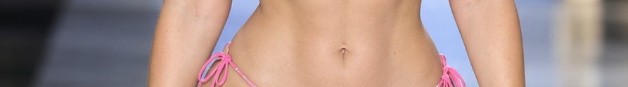 Close-up of a person's toned midsection wearing a bright pink tie-side string bikini bottom