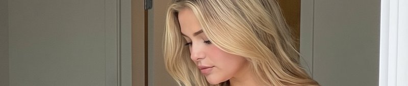 Close up portrait of a woman with long wavy blonde hair looking down indoors