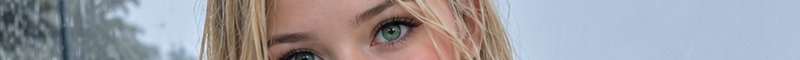 Extreme close up of a blonde woman's vivid green eyes with blurred frosted trees in the background