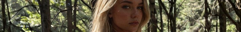 Close up horizontal portrait of a blonde woman with a serious expression, set against a sunlit fo...