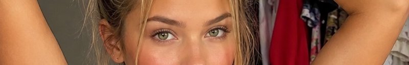Extreme close up of a blonde woman with bright light green eyes looking directly at the camera