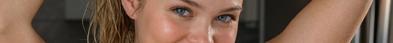 Extreme close up portrait of a woman with bright blue eyes, wet blonde hair, and dewy glistening ...