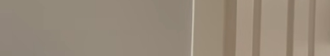 Smooth matte taupe interior wall next to vertical striped neutral fabric blinds