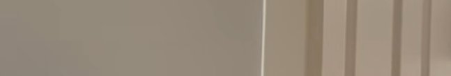 Smooth matte taupe interior wall next to vertical striped neutral fabric blinds
