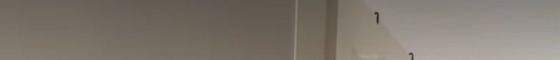 Narrow blurred horizontal strip of neutral taupe indoor walls with faint black number markings