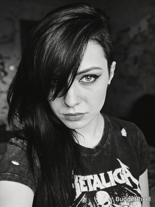 Monochrome selfie of alternative woman with asymmetrical dark hair, septum piercing, and distressed Metallica band tee