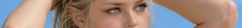 Extreme close-up of a blonde woman with light blue eyes holding her hands to her head against a b...