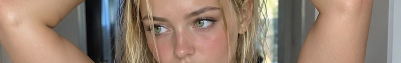 Extreme closeup of a blonde woman with wet hair and bright green eyes looking to the side