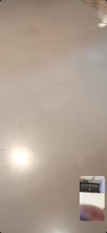 Textured beige indoor ceiling with bright recessed light and floating video call picture-in-pictu...