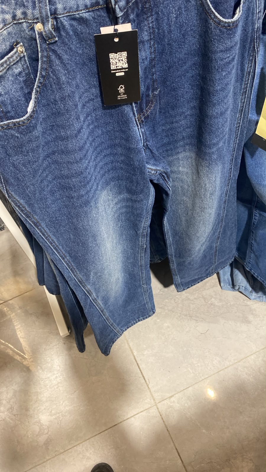 Faded medium-wash baggy denim jean shorts with a product hang tag hang on a retail clothing rack