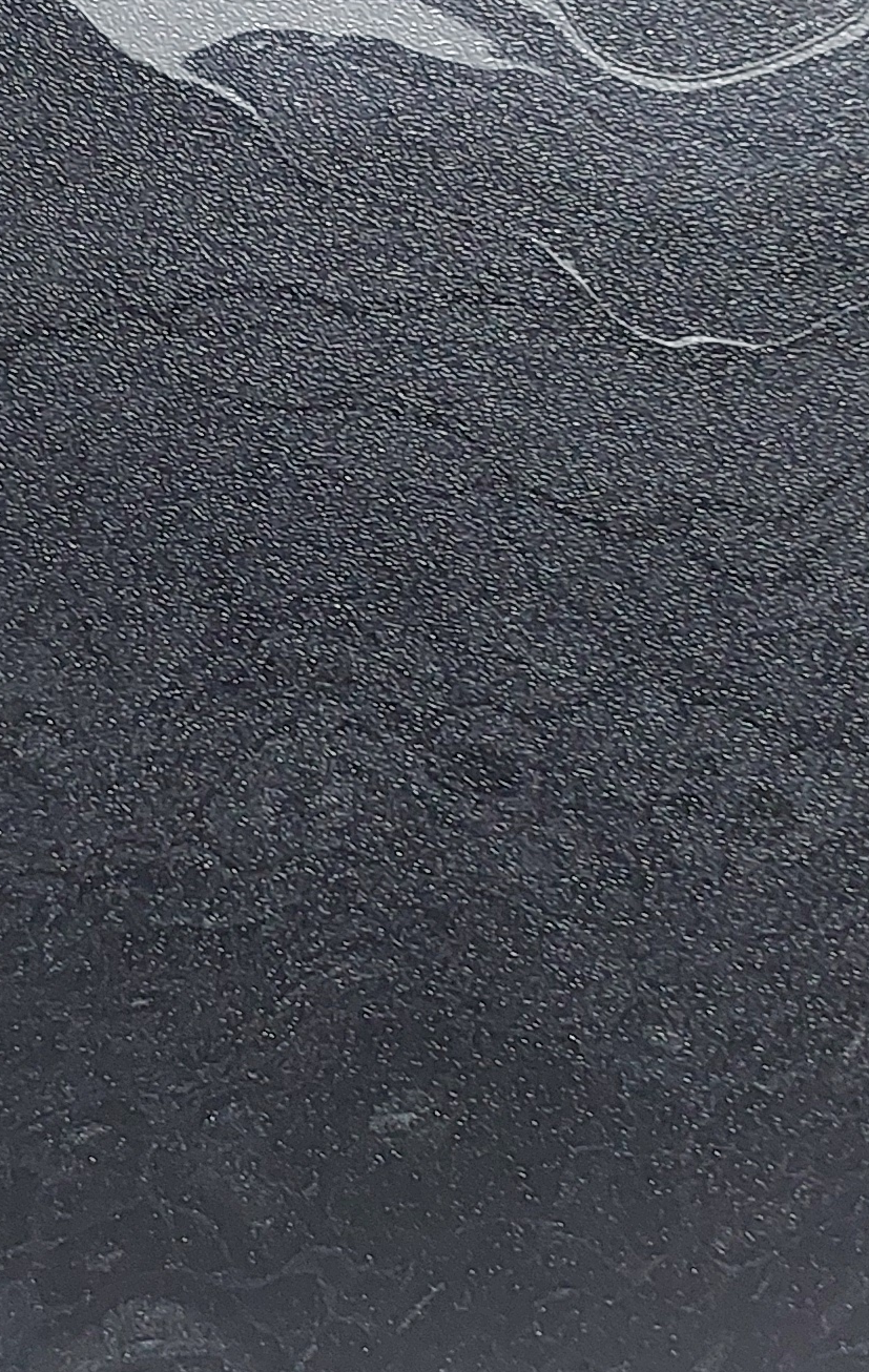 Close-up of a dark, granular textured surface with subtle curved light marks.