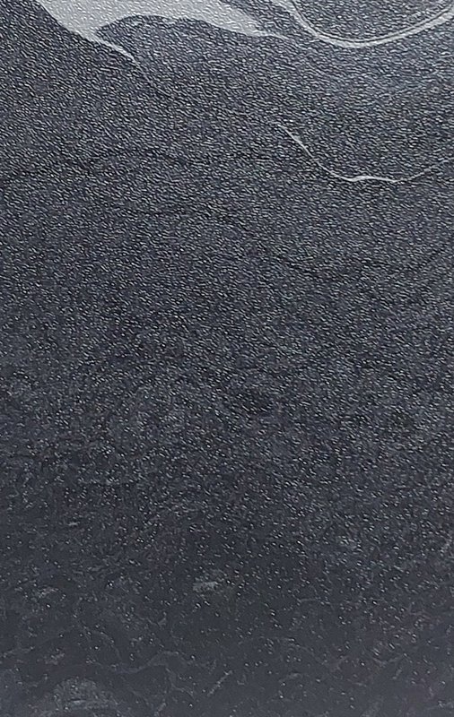 Close-up of a dark, granular textured surface with subtle curved light marks.