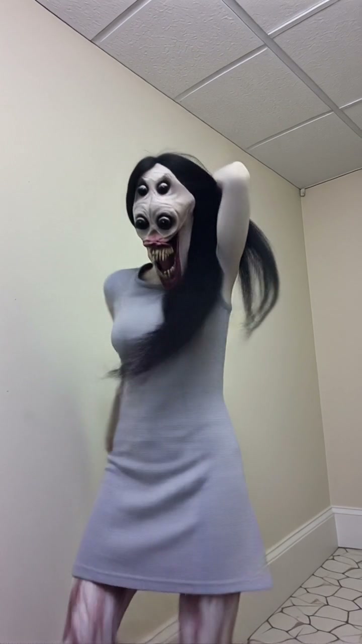 Grotesque uncanny horror monster with four bulging eyes, sharp fangs, and long black hair stands ...
