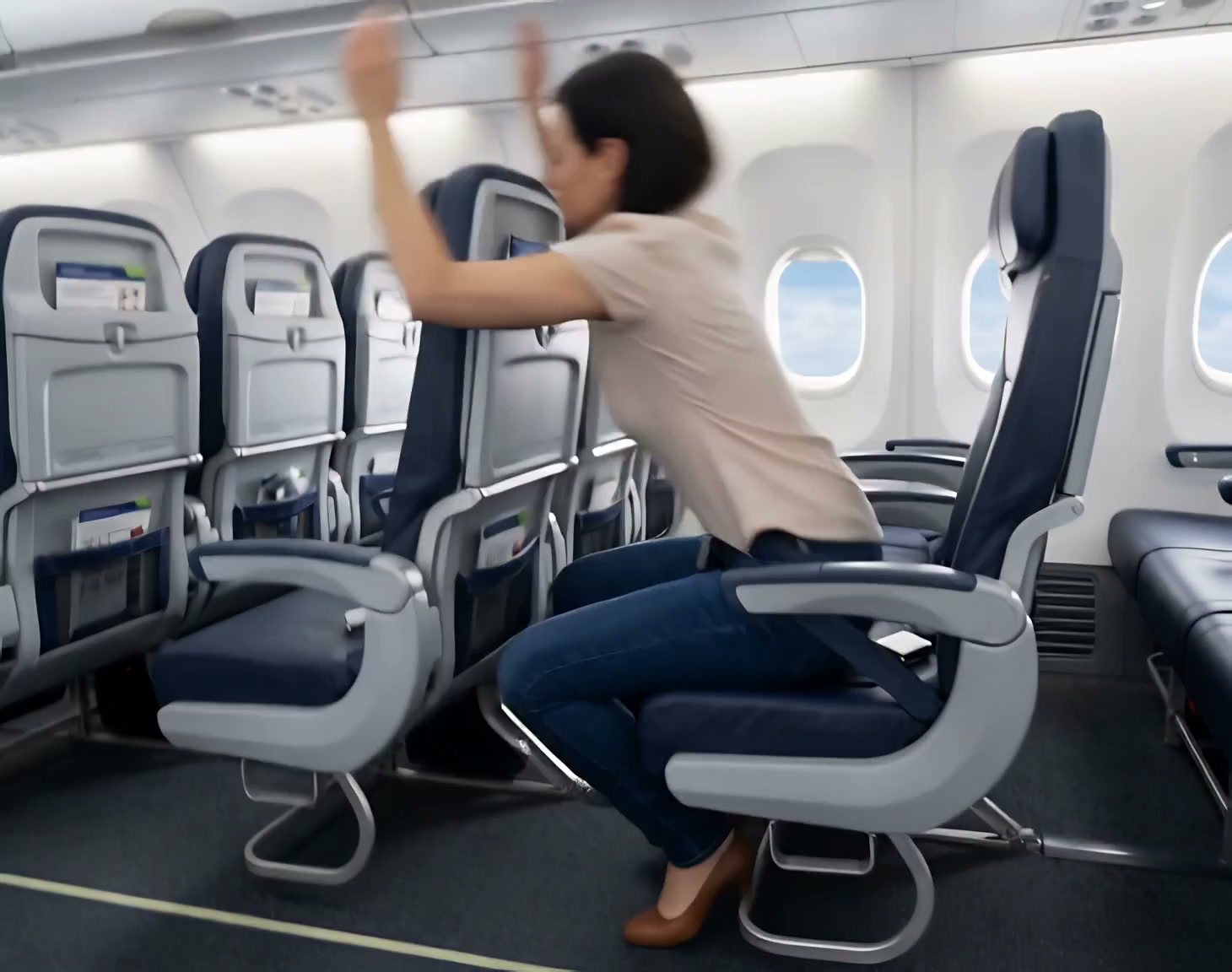 Woman stretching raised arms while seated in a commercial airplane cabin mid-flight