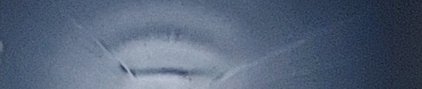 Blurry blue-toned close-up of a circular, concentric ring pattern on a reflective surface.