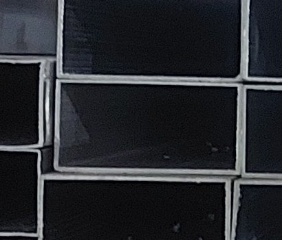 Close-up of glossy black rectangular tiles with light gray grout.