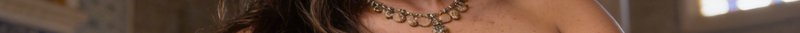 Close-up of a woman's neckline with layered gold jewelry and a sparkly pendant.