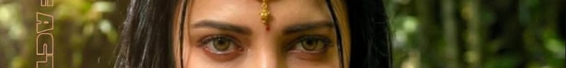 Close-up portrait of an Indian woman with a bindi and pendant in a sunlit green outdoor background