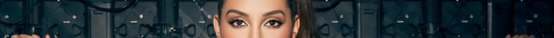 Close-up portrait of a woman with dramatic makeup against a dark, glossy backdrop.
