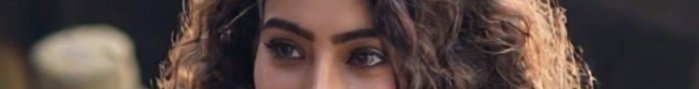 Close-up of a woman with curly brown hair and brown eyes.