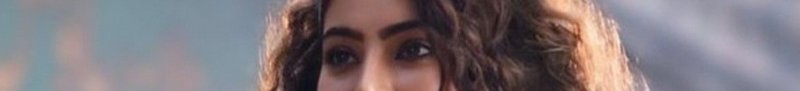 Close-up of a woman with curly hair outdoors, partial face, soft natural light.