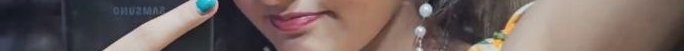 Close-up of a person’s face with turquoise nail polish, pink lipstick, and dangling earrings.