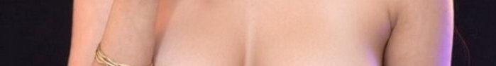 Close-up of a topless performer on stage bathed in warm lighting.