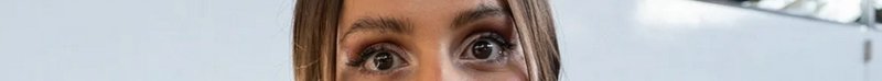 Close-up of a woman's eyes and forehead against a light background.