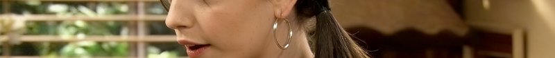 Close-up of a woman with a hoop earring indoors, partial face and ponytail visible.