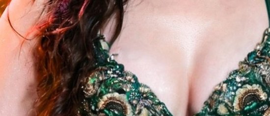 Close-up of a woman's décolletage in a green lace dress.
