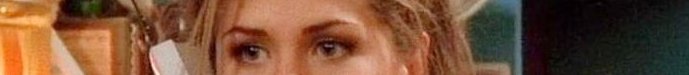 Close-up of a woman's eyes and hair in a warm indoor setting.