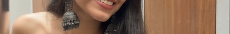 Close-up of a smiling woman wearing large silver tassel earrings.