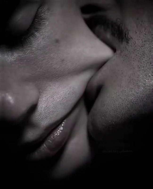 Close-up black-and-white kiss between two people, lips and noses touching.