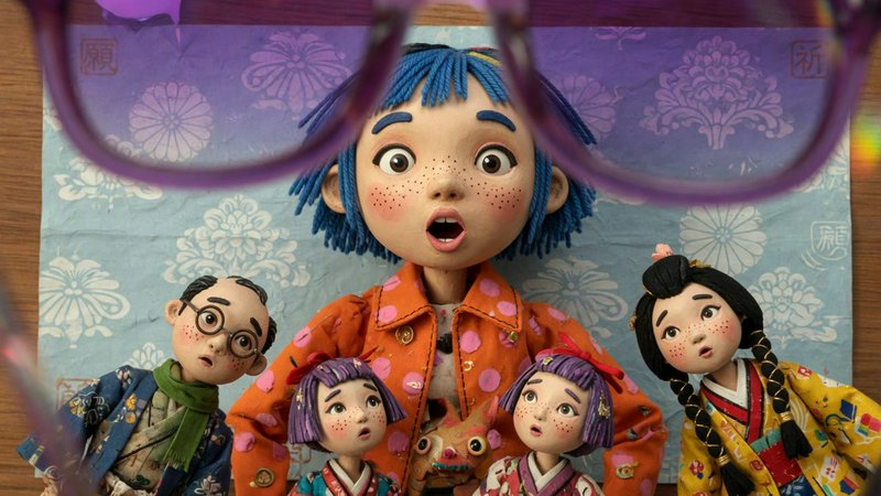 Close-up of wide-eyed surprised clay puppet group viewed through out-of-focus purple eyeglass frames