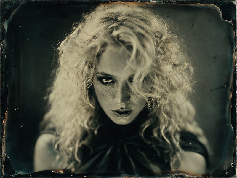 Intense vintage tintype portrait of a woman with wild curly blonde hair staring directly at the viewer