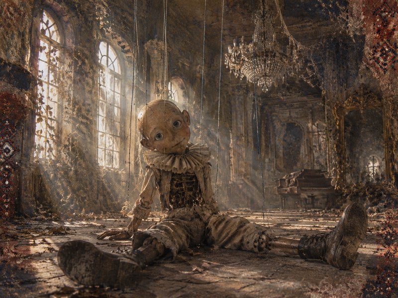 Weathered wooden Pinocchio marionette sits on the floor of a crumbling sunlit abandoned ballroom