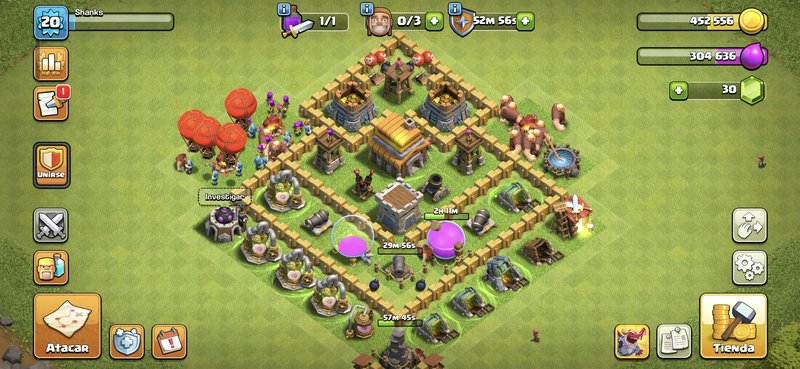 Clash of Clans base layout with layered walls, defenses, and resource storages on a green field.