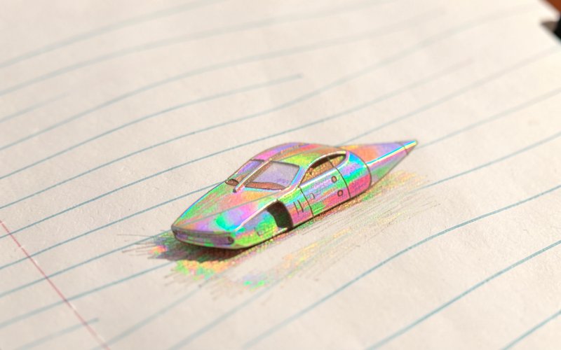 Tiny iridescent futuristic concept car resting on lined notebook paper