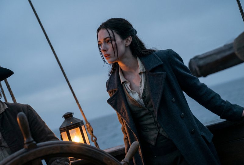 Woman on a sailing ship at dusk, wearing a dark coat, leaning on the railing with a lantern glow ...