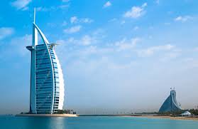 Iconic Burj Al Arab hotel rises over turquoise Dubai waters with a curved white resort nearby
