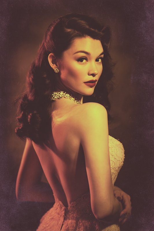 Vintage old Hollywood portrait of a glamorous woman looking over her shoulder, wearing a backless...