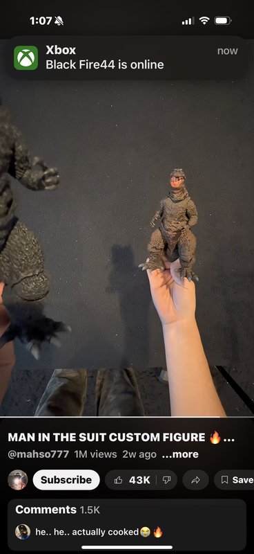 Hand holding a custom action figure of a reptilian man in a suit against a dark backdrop.