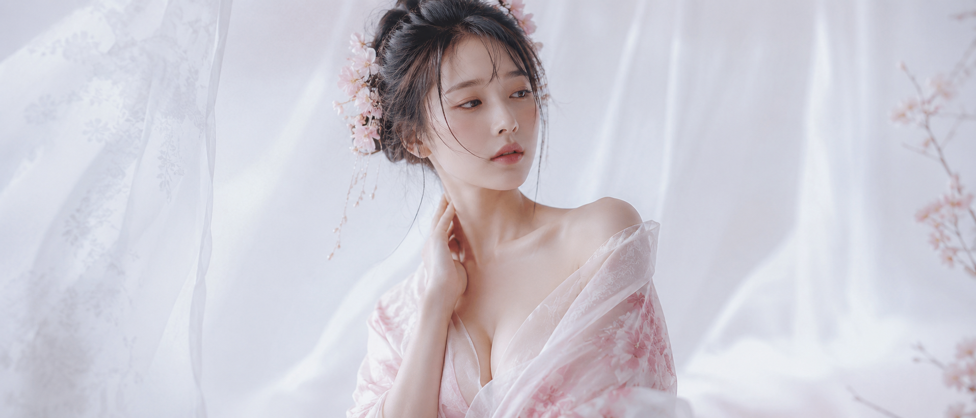 Ethereal portrait of a woman in soft pink sheer fabric and floral headpiece against a light pastel backdrop