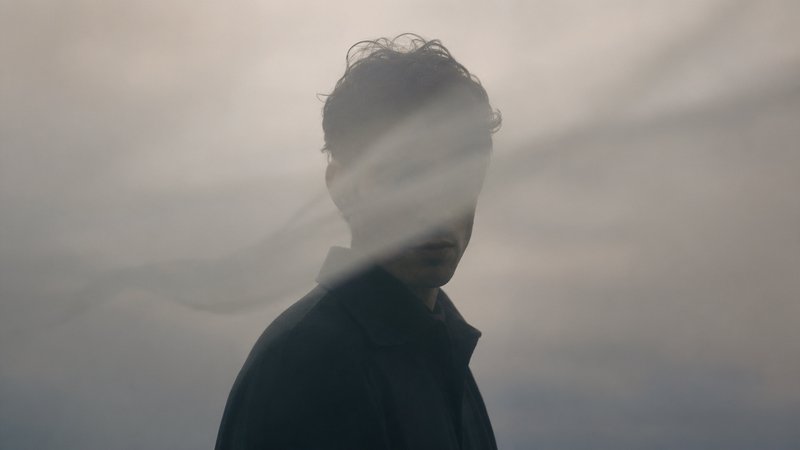 Silhouette of a person in a hazy, foggy overlay with soft, muted lighting.