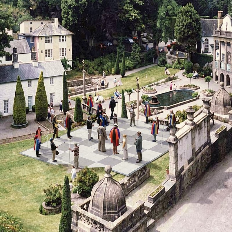 Aerial view of life-sized outdoor chessboard with human game pieces in a manicured historic estat...